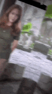a blurry picture of a woman in a green dress standing in front of a mirror