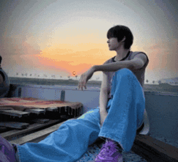 a person wearing blue jeans and purple shoes sits on a ledge