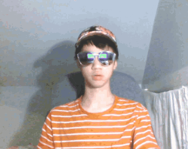 a boy wearing sunglasses and a baseball cap has the letter b on his glasses