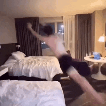 a man is jumping in the air in a hotel room while sitting on a chair .