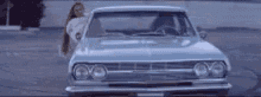 a woman is leaning out of a car window .