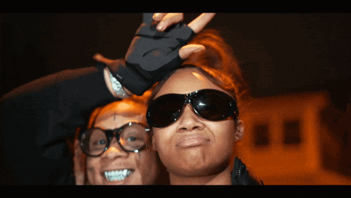 a man and a woman wearing sunglasses and gloves pose for a picture