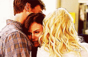 a man is hugging a woman who is crying while another woman looks on .