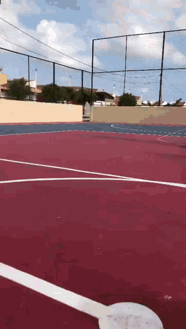 a red and blue basketball court with a fence surrounding it