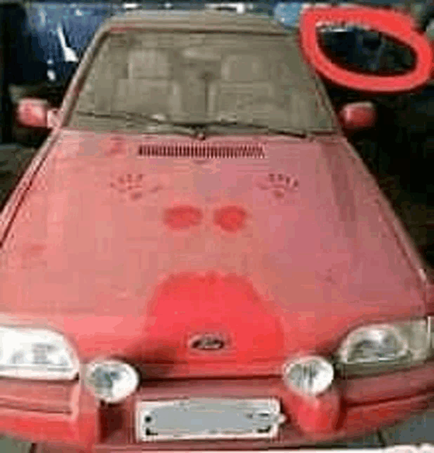 a red car is parked in a garage with a red circle around the hood .
