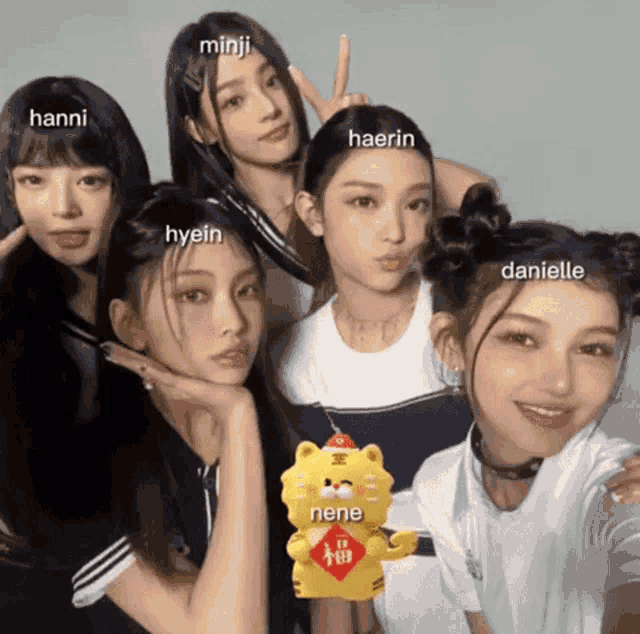 a group of girls are posing for a picture and one of them is holding a stuffed animal with the word nene on it