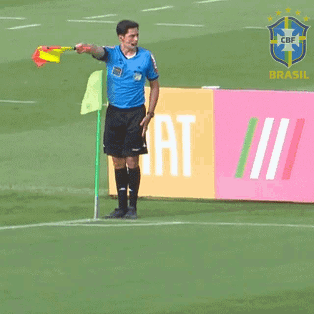 a soccer referee is holding a flag in front of a brasil sign
