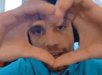 a man in a blue shirt is making a heart with his hands .