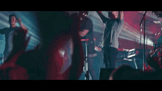 a group of people are dancing on a stage with their arms in the air