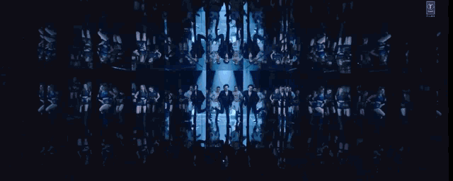 a group of people are dancing on a stage in front of a blue background