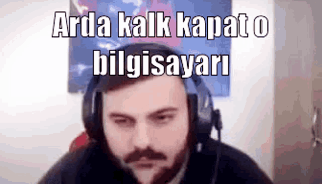 a man with a beard is wearing headphones and says arda kalk kapato bilgisayari .