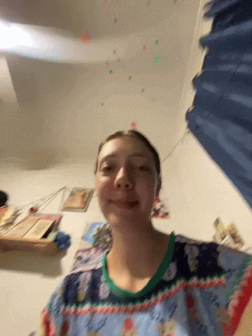 a girl wearing a christmas sweater looks at the camera
