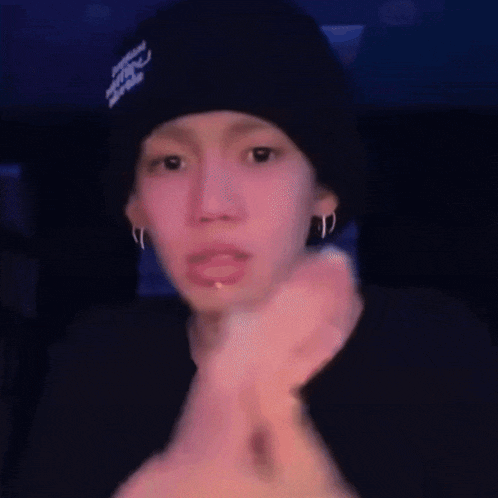 a person wearing a black beanie is pointing at the camera