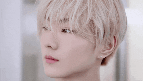 a close up of a person 's face with white hair and earrings