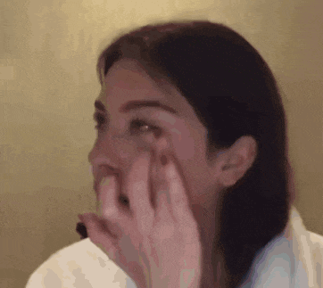 a woman is covering her face with her hands while looking at the camera .