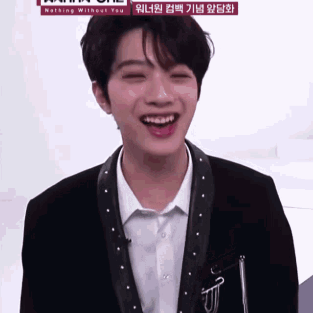 a young man in a suit is smiling in front of a nothing without you sign