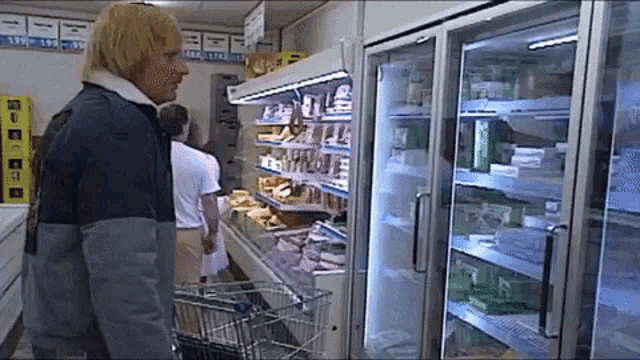 a man in a blue jacket stands in front of a refrigerator with a sign that says ' ice ' on it