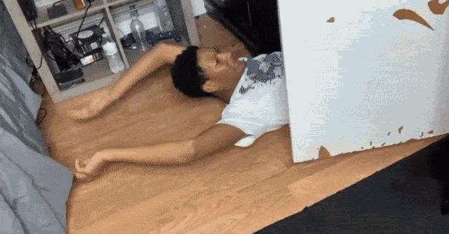 a person laying on a wooden floor with their arms outstretched