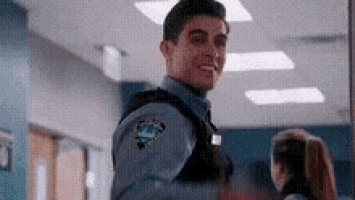 a man in a police uniform is standing in a hallway with a woman .