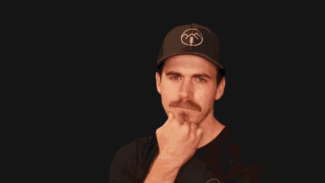 a man wearing a black hat with a mountain logo on it