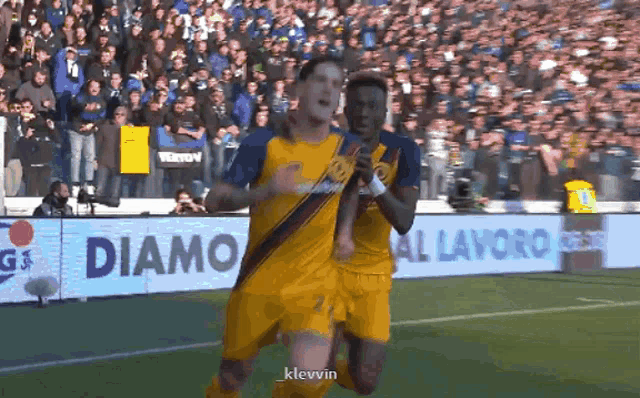 two soccer players are celebrating a goal in front of a banner for diamo