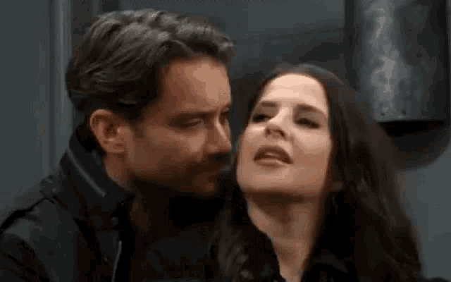 a man is kissing a woman on the forehead in a room .