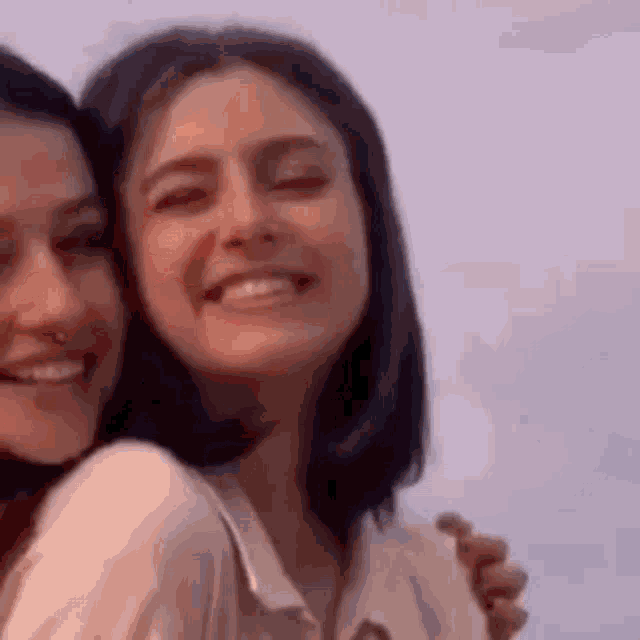 two women are hugging each other and smiling while standing next to each other .