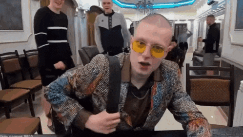 a man wearing yellow sunglasses is sitting at a table with other people