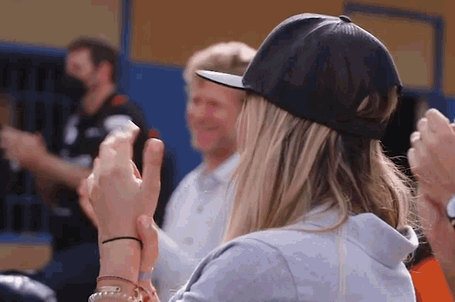 a woman wearing a black hat is clapping her hands in a crowd