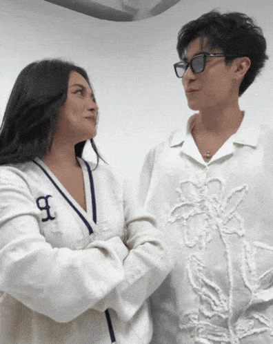 two women standing next to each other with one wearing a shirt with the letter b on it