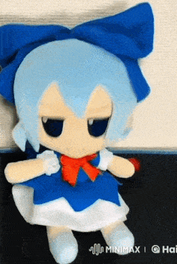 a stuffed doll with blue hair and a red bow sits on a black surface with the words minimax on the bottom right