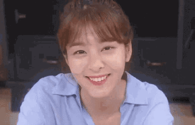 a close up of a woman wearing a blue shirt smiling .