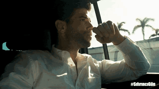 a man in a white shirt is sitting in a car with the hashtag #sfirncigun