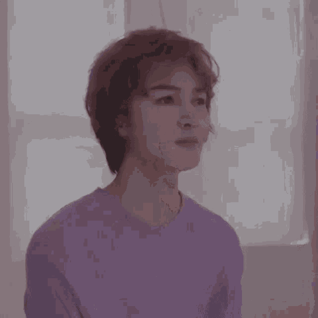 a young man with short hair is wearing a purple sweater .