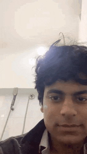 a man with curly hair is taking a selfie in a bathroom .