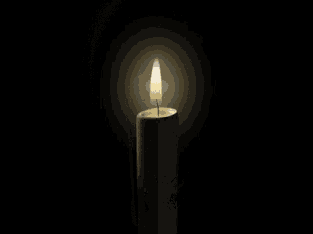 a candle with a picture of a man on it is lit up in the dark