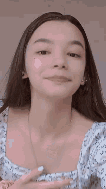 a close up of a woman 's face with a necklace and a floral top .