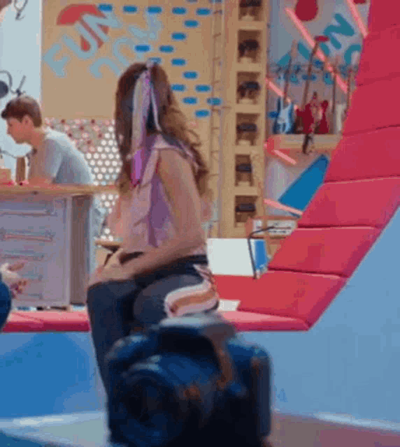 a woman is sitting on a suitcase in front of a sign that says fun on it