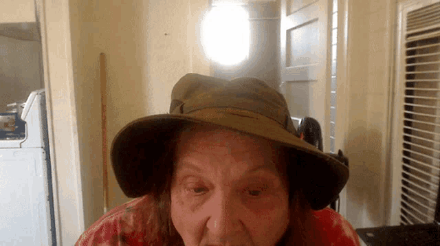 a woman wearing a hat is sitting in a kitchen
