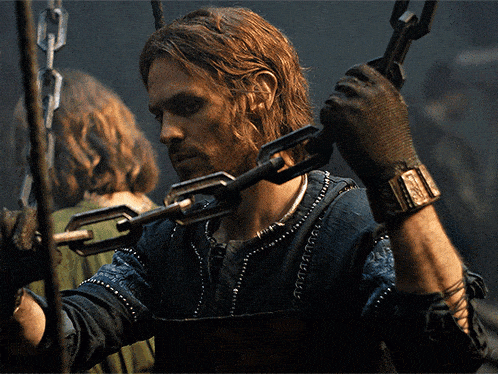 a man wearing gloves is holding a sword in his hands