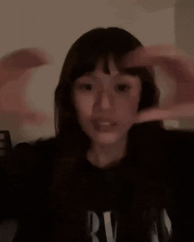 a young woman is making a heart shape with her hands .