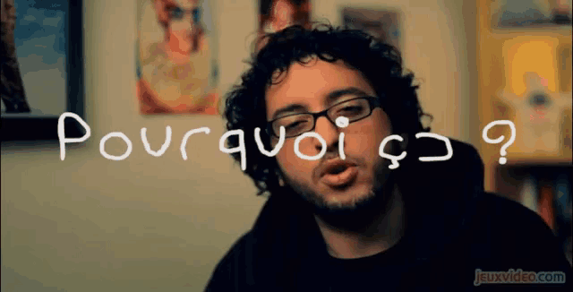 a man with curly hair and glasses says " pourquoi " in white letters