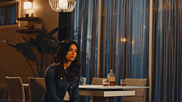 a woman in a denim jacket is standing in a living room