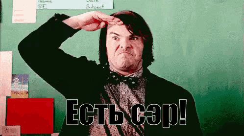 a man wearing a bow tie salutes in front of a green board with the words " есть cap " on it
