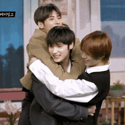 a group of young men are hugging each other in a living room .