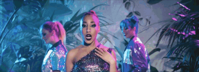 a woman in a sequined dress stands in front of a group of dancers