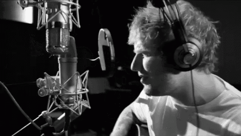 a man wearing headphones is singing into a microphone in a black and white photo