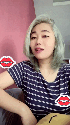 a woman wearing a blue and white striped shirt has a red lip sticker on her arm