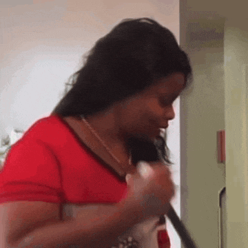 a woman in a red shirt is standing in a room holding a knife .