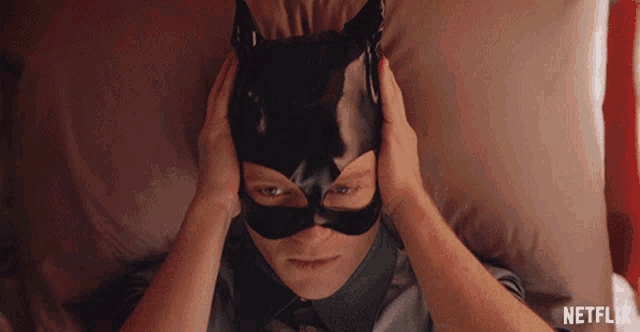 a man wearing a cat mask is laying on a bed with netflix written on the bottom